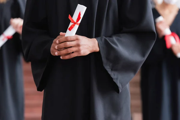 Vue recadrée du diplôme entre les mains de diplômés afro-américains — Photo de stock