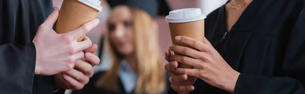 Cropped view of interracial graduates holding coffee to go, banner — Stock Photo