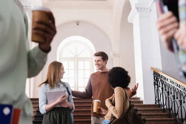 Étudiant souriant debout près d'amis multiethniques dans le hall de l'université — Photo de stock