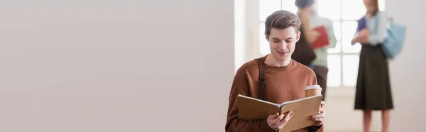 Estudante sorrindo com copo de papel olhando para notebook na universidade, banner — Fotografia de Stock