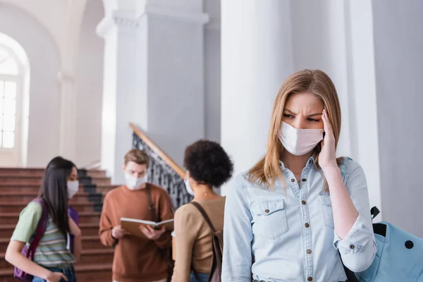 Estudiante enfermo en máscara médica de pie en la universidad - foto de stock