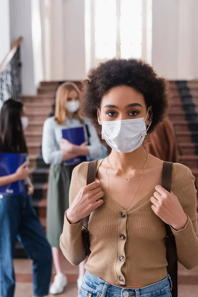 African american student in medical mask looking at camera in university — Stock Photo