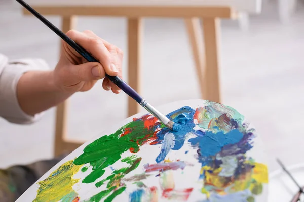 Cropped view of mature woman holding palette and paintbrush — Stock Photo