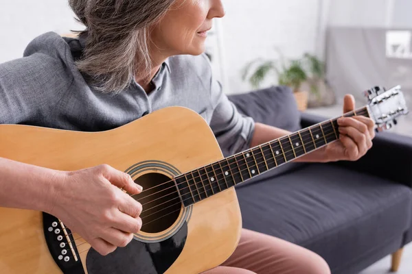 Vista ritagliata di donna di mezza età con i capelli grigi suonare la chitarra acustica — Foto stock
