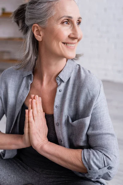 Счастливая зрелая женщина с седыми волосами и молящимися руками — стоковое фото