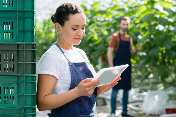 Smiling african american farmer using digital tablet near colleague on blurred background — Stock Photo