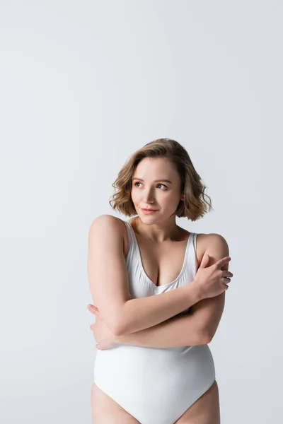 Donna in sovrappeso e timida con braccia incrociate posa isolata su bianco — Foto stock