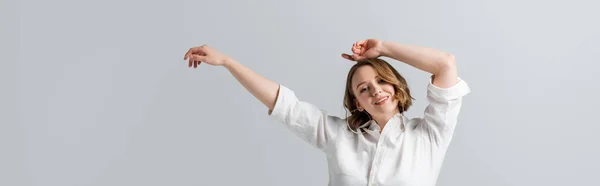 Sobrepeso e mulher satisfeita em camisa branca posando com as mãos acima da cabeça isolado em cinza, banner — Fotografia de Stock