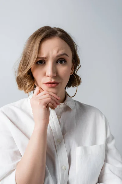 Mujer con sobrepeso pensativa en camisa blanca aislada en gris - foto de stock