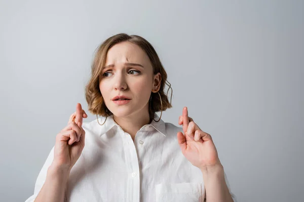 Young overweight woman in white shirt with crossed fingers isolated on grey — Stock Photo