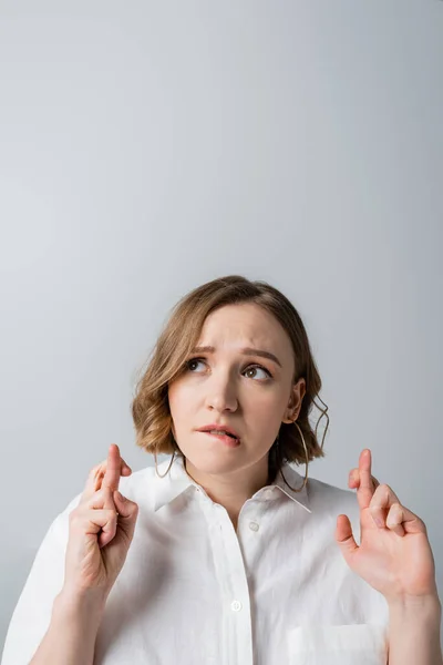 Femme en surpoids en chemise blanche avec les doigts croisés isolés sur gris — Photo de stock