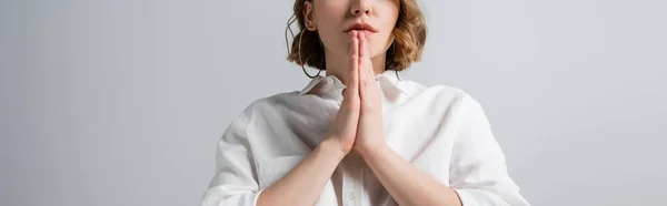 Cropped view of young overweight woman in white shirt with praying hands isolated on grey, banner — Stock Photo