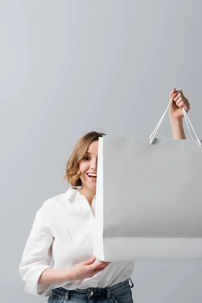 Happy overweight woman in white shirt holding shopping bag on grey — Stock Photo