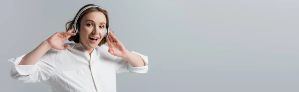 Heureuse femme taille plus dans les écouteurs sans fil écouter de la musique isolée sur gris, bannière — Photo de stock