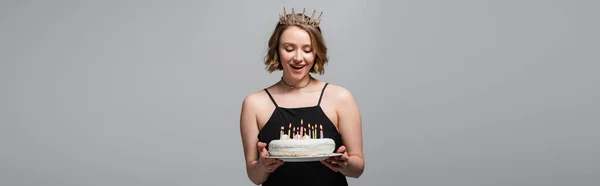 Felice plus size donna in abito antiscivolo e corona con torta di compleanno isolata su grigio, banner — Foto stock