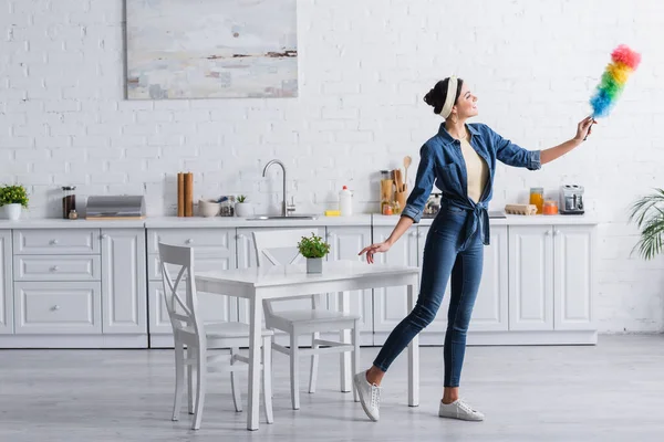 Femme au foyer joyeuse regardant brosse à poussière dans la cuisine — Photo de stock