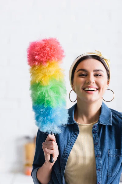 Femme au foyer avec brosse à poussière souriant à la caméra — Photo de stock