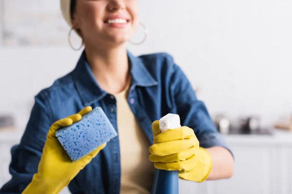 Vista ritagliata di detergente e spugna sfocata nelle mani della donna sorridente — Foto stock