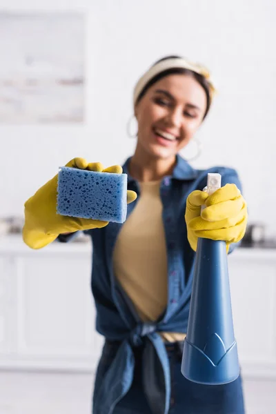 Губка і миючий засіб в руках розмитої домогосподарки — стокове фото