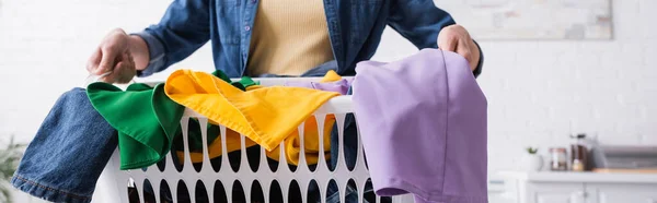 Vista recortada de la cesta con ropa en las manos de la mujer en la cocina, pancarta - foto de stock