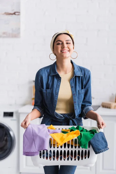 Cheerful housewife holding basket with clothes at home — Stock Photo
