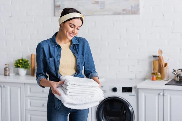 Alegre dona de casa no denim camisa olhando para branco toalhas — Fotografia de Stock