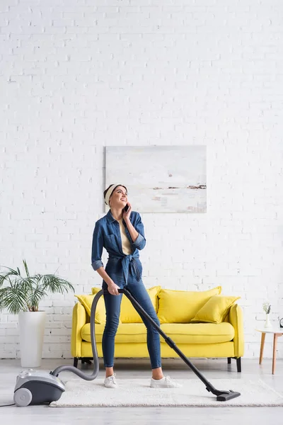 Sorrindo dona de casa falando no smartphone e tapete de limpeza — Fotografia de Stock