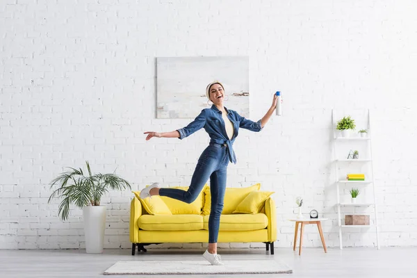 Alegre ama de casa con ambientador en casa - foto de stock