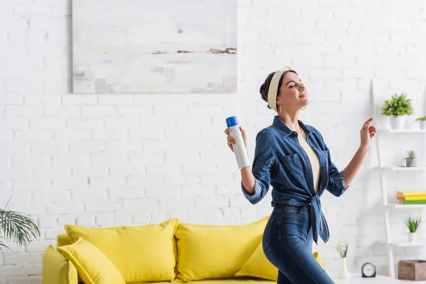 Young woman holding bottle of air freshener at home — Stock Photo