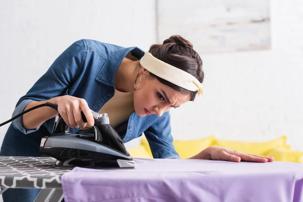 Konzentrierte Hausfrau bügelt Kleidung an Bord — Stockfoto