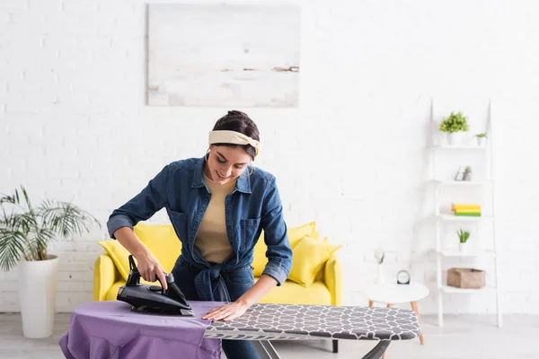 Smiling housewife ironing clothes in living room — Stock Photo