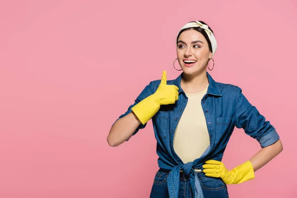 Alegre ama de casa en guantes de goma mostrando como gesto aislado en rosa - foto de stock