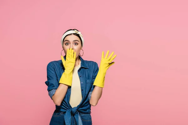 Amazed housewife in rubber gloves looking at camera isolated on pink — Stock Photo