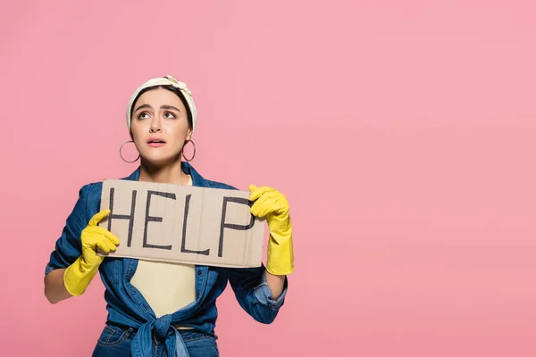 Junge Hausfrau in Gummihandschuhen hält Plakat mit Hilfe von Schriftzug isoliert auf rosa — Stockfoto