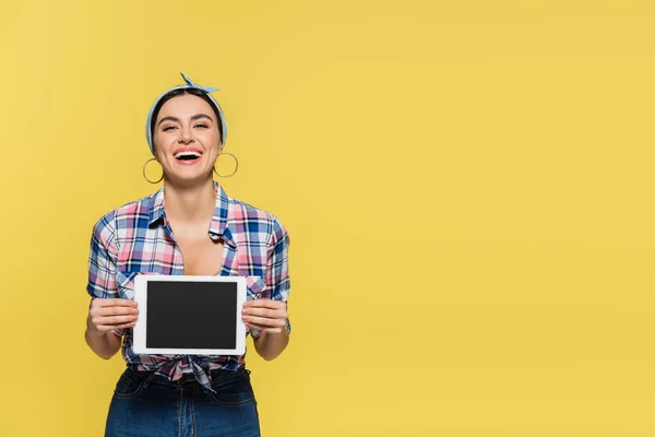 Fröhliche Hausfrau hält digitales Tablet isoliert auf gelb — Stockfoto