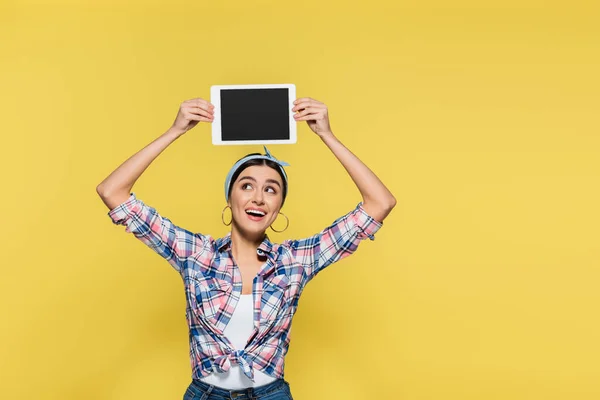 Sorrindo dona de casa na cabeça segurando tablet digital no fundo amarelo — Fotografia de Stock