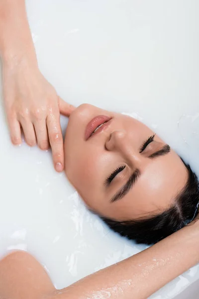 Vue aérienne de la femme les yeux fermés touchant le cou tout en prenant un bain de lait — Photo de stock