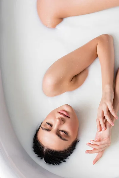 Вид зверху чуттєвої молодої жінки, що розслабляється у ванні з молоком — стокове фото