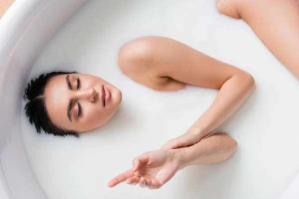 Verführerische Frau mit geschlossenen Augen genießt Milchbad — Stockfoto