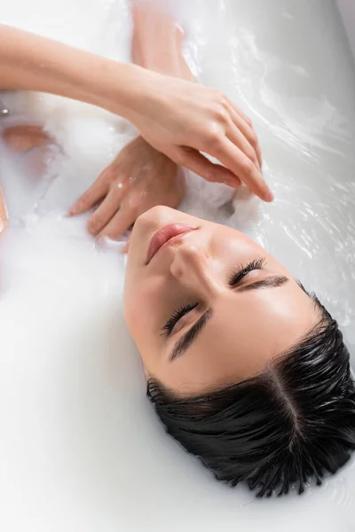 Overhead view of sensual woman with closed eyes bathing in milk — Stock Photo