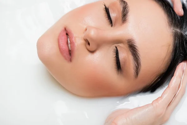 Close up view of female face in milk bath — Stock Photo