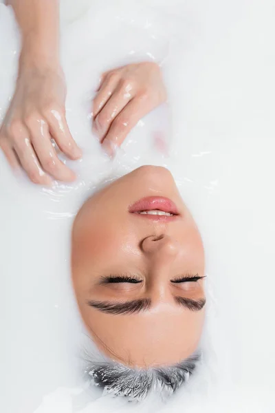 Vista superior de la joven mujer disfrutando bañándose en leche - foto de stock