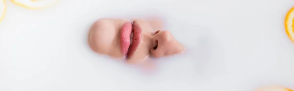 Top view of female face immersed in milk bath, banner — Stock Photo