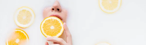 Вид сверху женщины с апельсиновым ломтиком в молочной ванне, баннер — стоковое фото