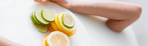 Partial view of woman taking milk bath near slices of fresh citruses, banner — Stock Photo