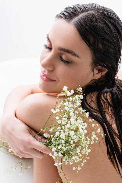 Mujer sonriente con flores blancas, diminutas tomando baño de leche - foto de stock