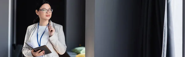 Mujer de negocios asiática sosteniendo pluma y cuaderno en la oficina, bandera - foto de stock