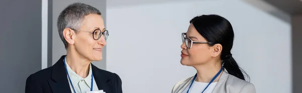 Sorridente donna d'affari guardando collega asiatico in ufficio, banner — Foto stock