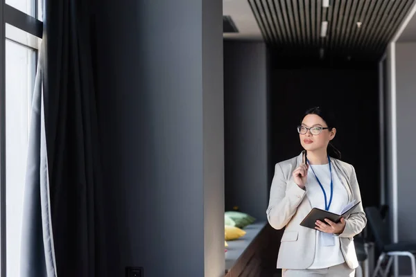 Asian businesswoman in suit holding notebook and pen in office — Stock Photo