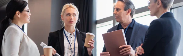 Mujer de negocios con tableta digital y café para ir mirando a colegas multiétnicos, pancarta — Stock Photo
